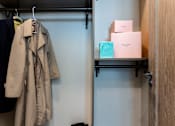 Thumbnail 17 of 33 - A beige trench coat is hanging on a hook.