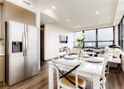 Thumbnail 8 of 33 - A modern kitchen with a refrigerator, table, and chairs.