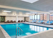 Thumbnail 31 of 33 - A large indoor swimming pool with lounge chairs and a glass wall.