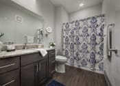 Thumbnail 15 of 44 - Master bathroom with floating vanities, quartz countertops, backlit vanity mirror, walk-in shower with Euro shower door and quartz-topped bench seat at The Ivy at Berlin Place, South Bend, Indiana
