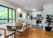 Thumbnail 6 of 21 - A dining room with hardwood-style flooring and a modern pendant light near a kitchen and double sliding doors leading to a private balcony.