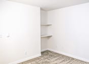 Thumbnail 9 of 17 - A room with a carpeted floor and a wall-mounted shelf.