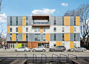 Thumbnail 2 of 43 - A modern multi-story building with a balcony on the top floor.