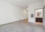 Thumbnail 28 of 43 - A large empty room with a doorway leading to a kitchen area.