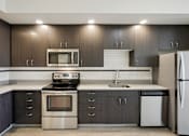 Thumbnail 7 of 43 - A modern kitchen with dark brown cabinets and stainless steel appliances.