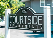 Thumbnail 11 of 17 - A sign for Courtside Apartments is displayed in front of a building.