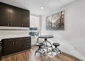 Thumbnail 41 of 43 - A kitchen with dark wood cabinets and a white backsplash with a bar area and a table with two stools.