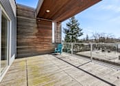 Thumbnail 42 of 43 - A wooden deck with a blue chair and a wooden house.