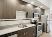 Thumbnail 8 of 43 - A modern kitchen with dark wood cabinets and stainless steel appliances.