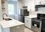 Thumbnail 13 of 17 - A modern kitchen with a white countertop and stainless steel appliances.