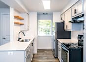 Thumbnail 16 of 17 - A kitchen with black appliances and white cabinets.