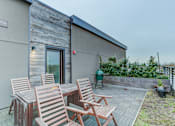 Thumbnail 7 of 11 - a patio with wooden chairs and a table outside of a house