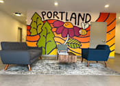 Thumbnail 3 of 43 - A room with a Portland mural on the wall and two chairs and a table in front of it.