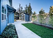 Thumbnail 22 of 55 - A blue house with a white walkway leading to a small building.