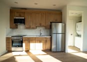 Thumbnail 25 of 55 - A kitchen with wooden cabinets and a stainless steel refrigerator.