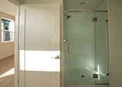 Thumbnail 32 of 55 - A bathroom with a glass shower stall and a white door.