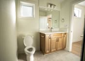 Thumbnail 33 of 55 - A white toilet sits in a bathroom with a wooden cabinet and a mirror above it.