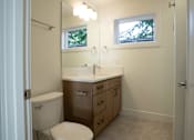 Thumbnail 50 of 55 - A white toilet sits in a bathroom with a sink and mirror.
