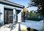 Thumbnail 9 of 55 - A blue building with a black gate and a tree in front.