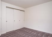Thumbnail 1 of 17 - A room with a carpeted floor and a white wall with a white closet door.