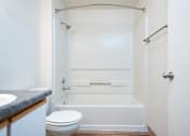 Thumbnail 4 of 17 - A white bathroom with a toilet, sink, and bathtub.