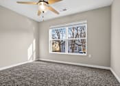 Thumbnail 23 of 30 - A room with a ceiling fan and a window showing a view of houses.