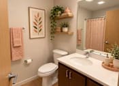 Thumbnail 11 of 16 - A bathroom with a toilet, sink, and a mirror.