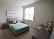 Thumbnail 12 of 22 - A bedroom with a bed, nightstand, chair, and a painting on the wall.