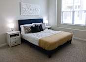 Thumbnail 11 of 22 - A bedroom with a bed, nightstand, and a painting on the wall.