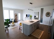 Thumbnail 7 of 22 - A kitchen with a refrigerator, sink, and a dining table with chairs.