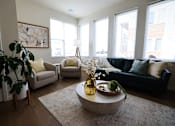 Thumbnail 9 of 22 - A living room with a large couch, a coffee table, and a potted plant.