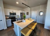 Thumbnail 7 of 22 - a kitchen with a large island with three stools at The Daniels at Northern Gateway Apartments, Wisconsin