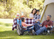 Thumbnail 12 of 22 - a family sitting at a picnic table outside a tent at The Daniels at Northern Gateway Apartments, Saukville, WI
