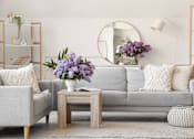 Thumbnail 2 of 8 - A living room with a couch, a coffee table, and a round mirror on the wall.