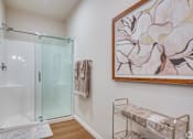 Thumbnail 20 of 22 - A bathroom with a glass shower door and a painting on the wall.