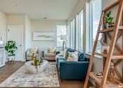 Thumbnail 16 of 22 - A living room with a blue couch and a wooden ladder.