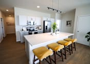 Thumbnail 7 of 30 - A kitchen with a white island and yellow bar stools.