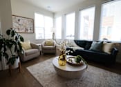 Thumbnail 10 of 30 - A living room with a large couch, a coffee table, and a potted plant.