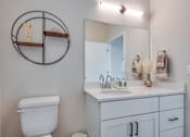Thumbnail 20 of 30 - A bathroom with a toilet, sink, and mirror.