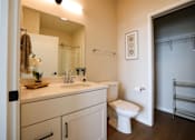 Thumbnail 15 of 30 - A white toilet sits in a bathroom next to a sink and a mirror.