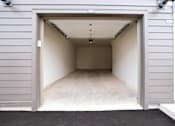 Thumbnail 22 of 30 - A garage door is open to reveal a clean, empty garage inside.