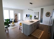 Thumbnail 8 of 30 - A kitchen with a refrigerator, sink, and a dining table with chairs.