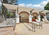 Thumbnail 25 of 28 - A building with a white roof and arched openings has a concrete wall in front of it.