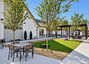 Thumbnail 28 of 29 - A patio with a table and chairs is surrounded by trees.