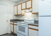 Thumbnail 15 of 37 - A white fridge sits in a kitchen with wooden cabinets.