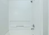 Thumbnail 26 of 37 - A white bathroom with a shower and a door.