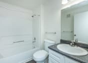 Thumbnail 25 of 37 - A white bathroom with a toilet, sink, and bathtub.