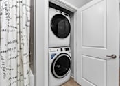 Thumbnail 22 of 34 - A white washing machine is in a small white cabinet.