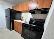 Thumbnail 4 of 15 - A black oven and fridge in a kitchen with wooden cabinets.
