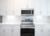 Thumbnail 63 of 67 - a kitchen with white cabinets and a stainless steel stove